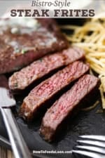 A close-up view of a reverse-seared New York strip steak that has been cut into strips sitting on a plate next to shoestring French fries.