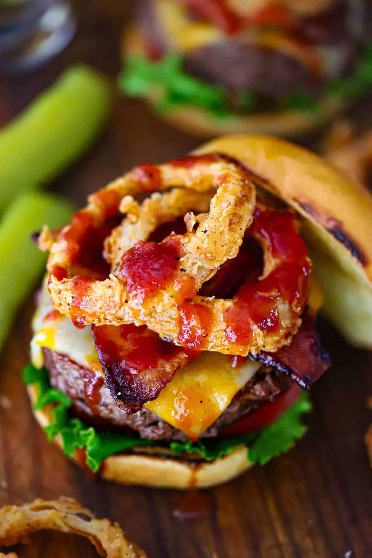 An overhead view of a BBQ Bacon Burger that is topped with steakhouse onion rings and crispy bacon all drizzled with homemade BBQ sauce.