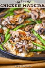 A close-up view of a cast-iorn skillet filled with chicken Madeira with mushrooms and asparagus.