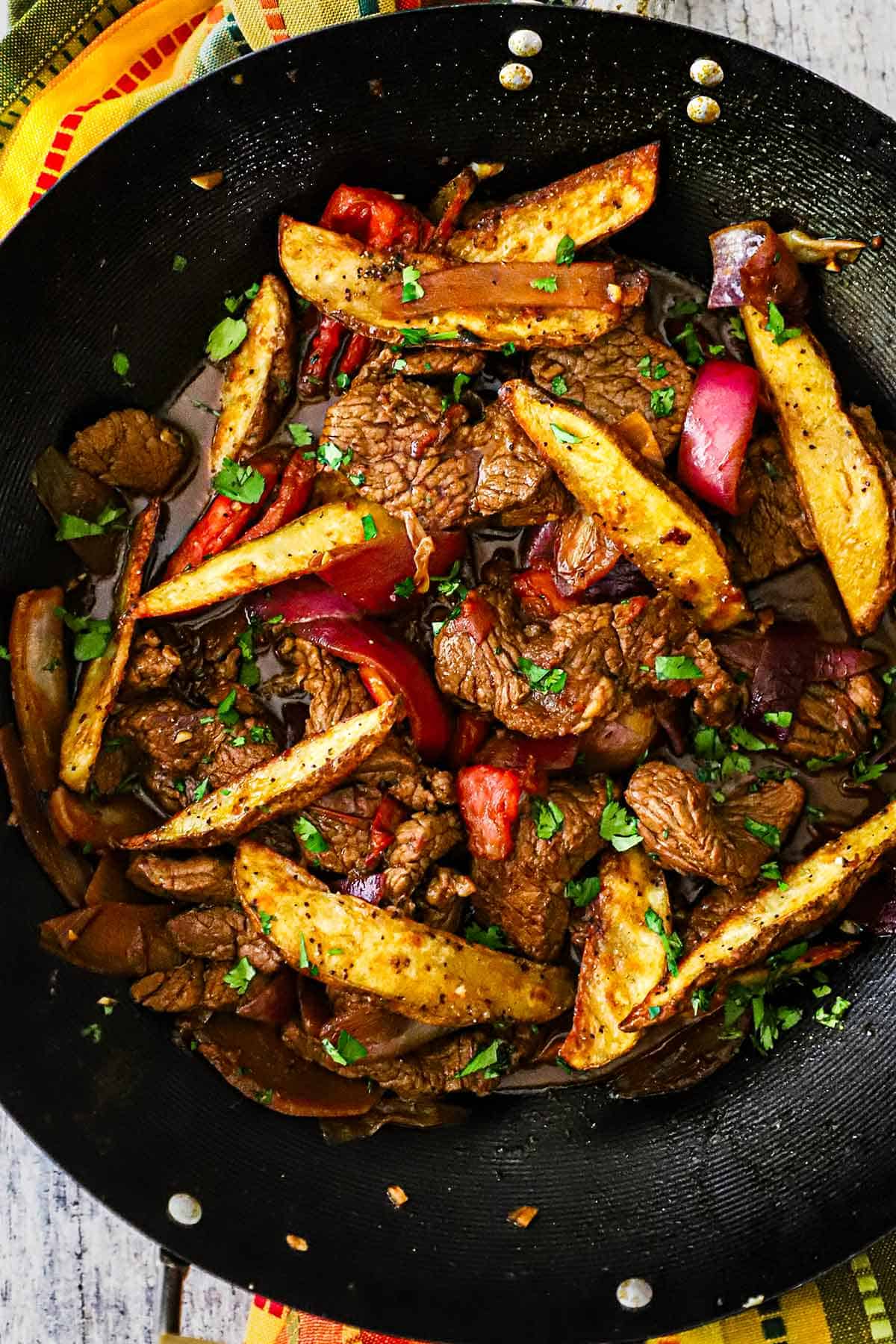 An overhead view of a wok that is filled with freshly prepared Classic Lomo Saltado, Peruvian Steak and Potatoes Stir-fry.
