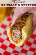 A person holding a partially eaten NYC-style sausage and peppers on an Italian roll.