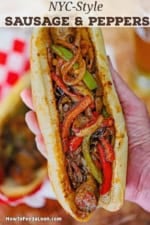 A person holding a large NYC-Style Sausage and Peppers in an Italian roll in the palm of his hand.
