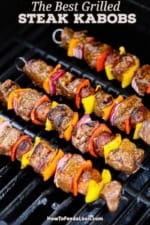 Four steak kabobs being grilled on a gas stove.
