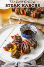 All the components to grilled steak kabobs off the skewer on a white dinner.