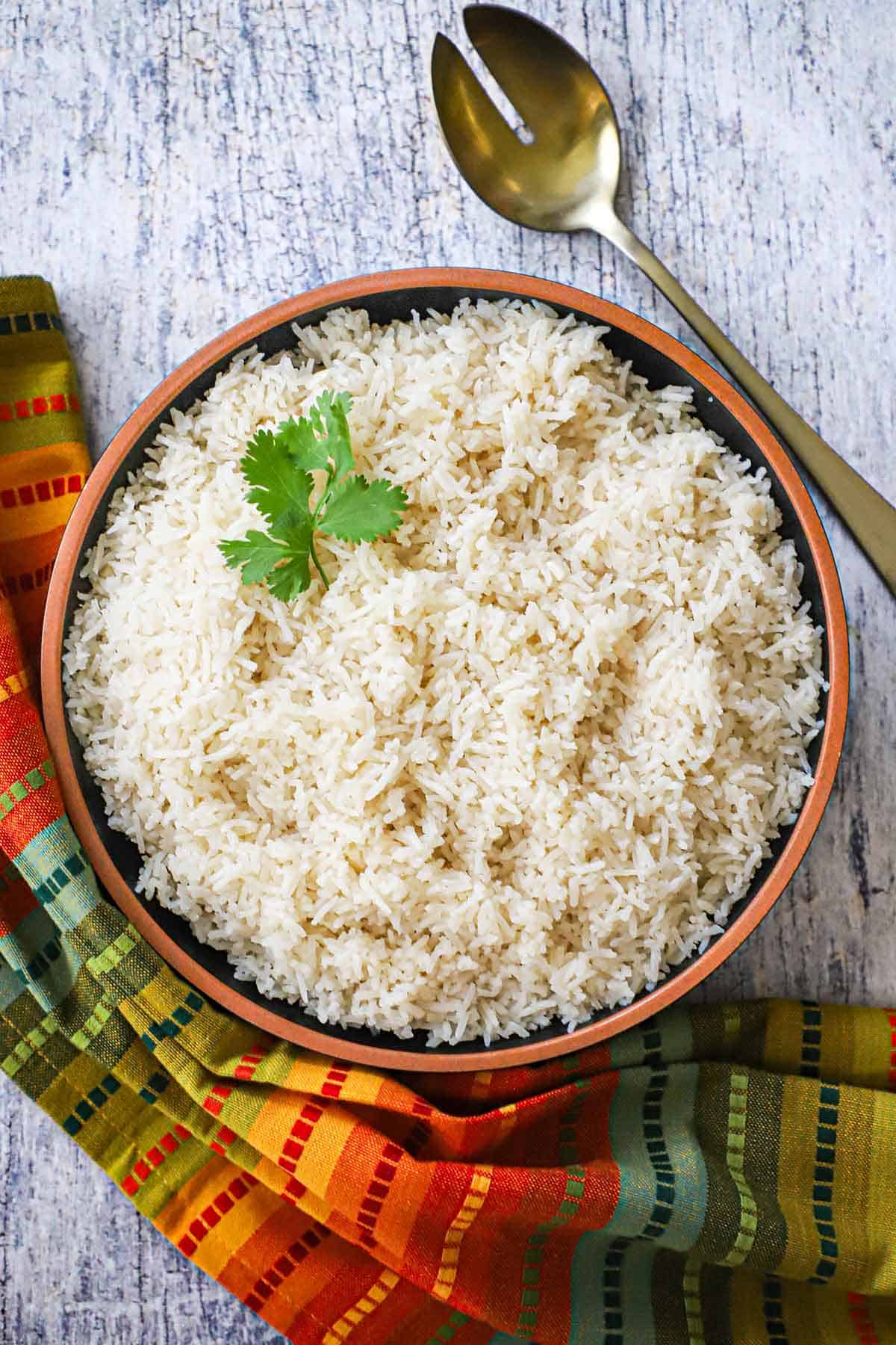 An overhead view of a large bowl filled with Peruvian Garlic Rice and garnished with a sprig of fresh cilantro.