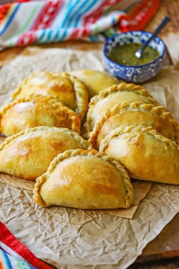 A straight-on view of two rows of Argentine Beef Empanadas on a sheet of crinkled brown paper.