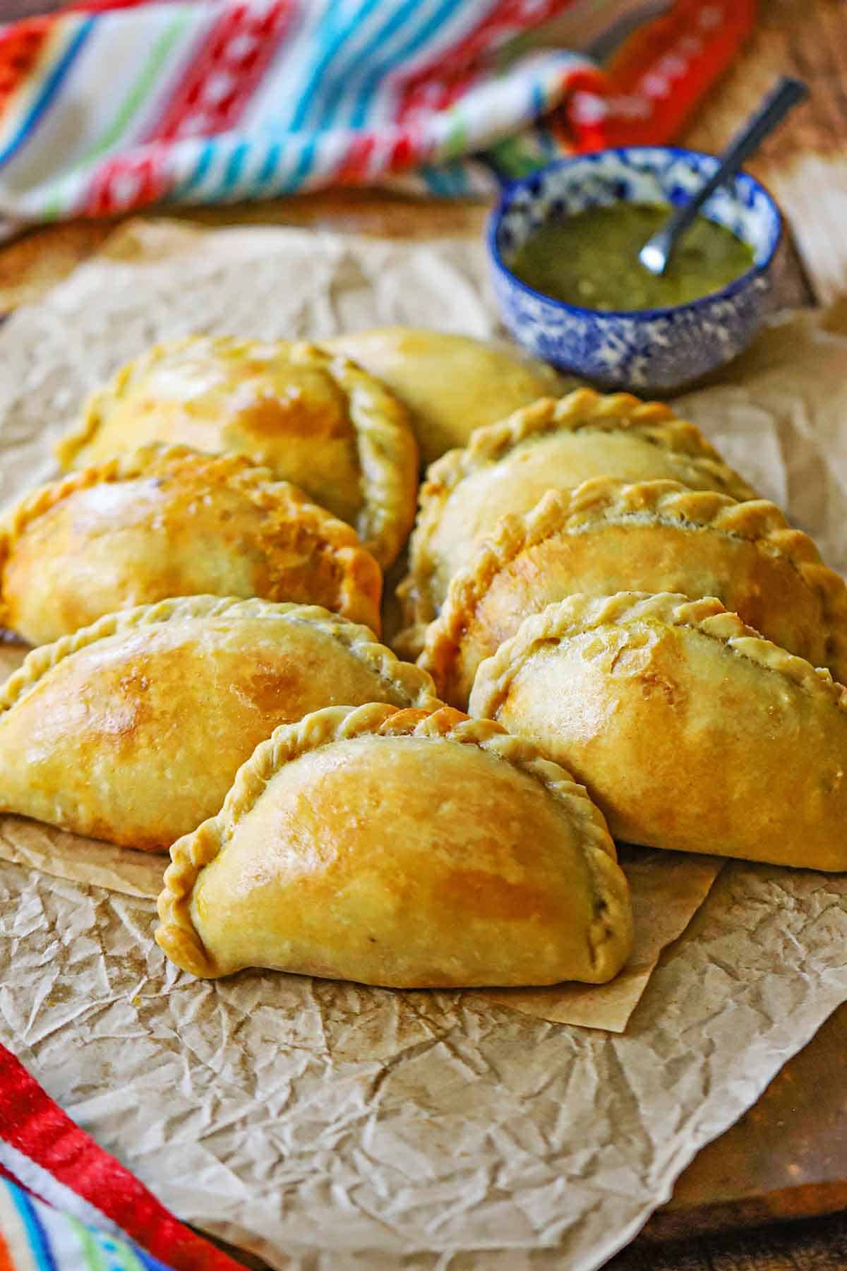 A straight-on view of two rows of Argentine Beef Empanadas on a sheet of crinkled brown paper.