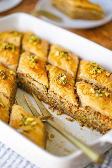 Close-up of authentic Greek baklava in a pan, showing the crispy, flaky phyllo layers and honey-soaked walnut and pistachio filling.