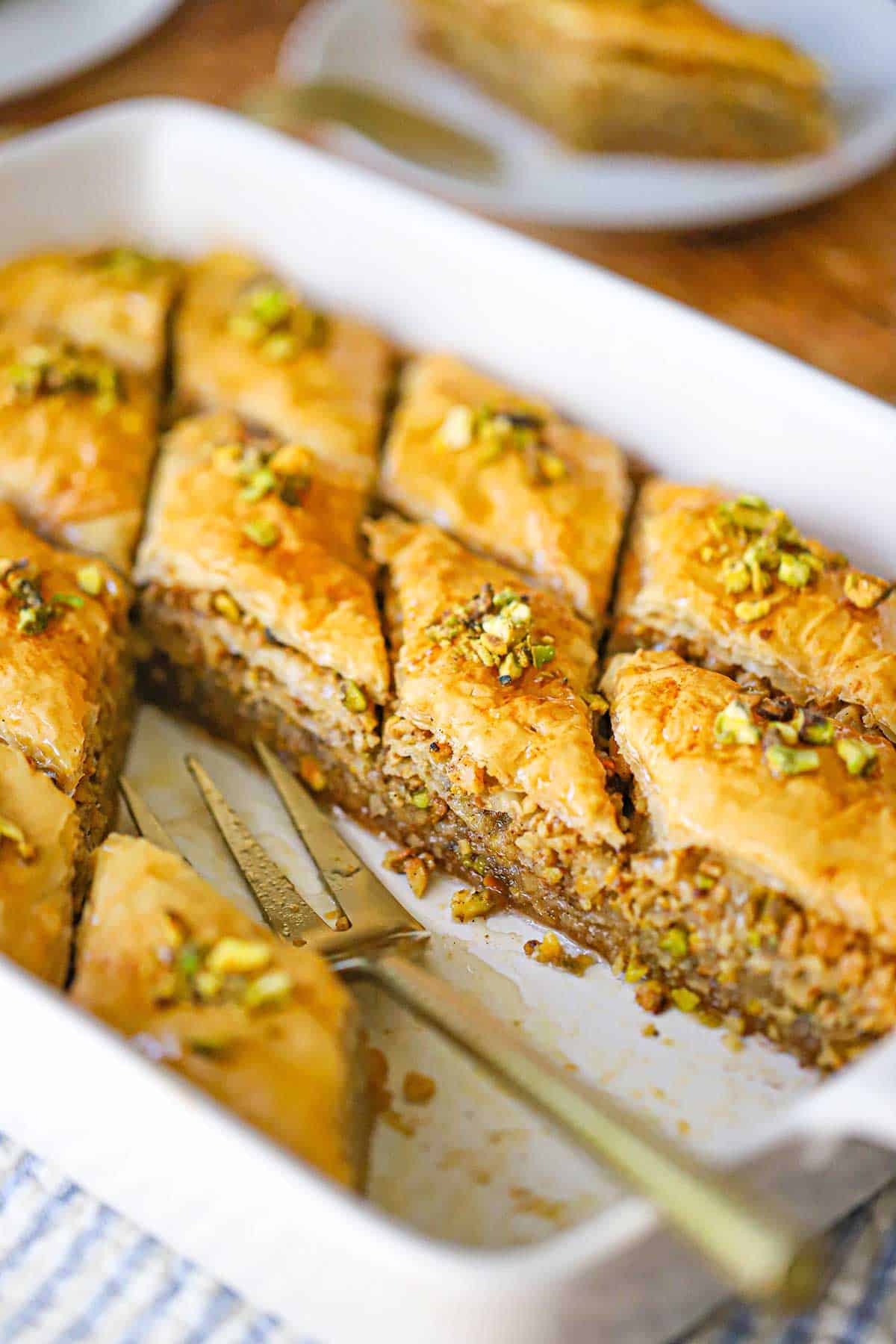 Close-up of authentic Greek baklava in a pan, showing the crispy, flaky phyllo layers and honey-soaked walnut and pistachio filling.