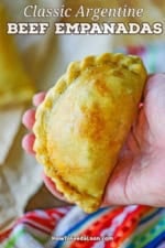A person holding a classic Argentine beef empanada in the palm of his hand.