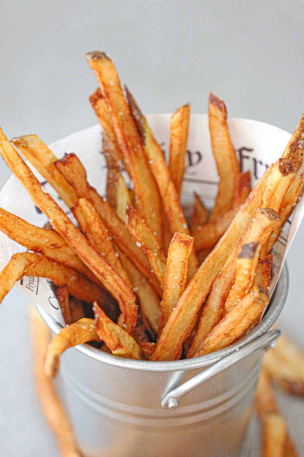 A close-up view of homemade French fries in a small metal pale.