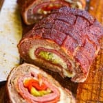 A Smoked Italian Fatty that has been cut into three large pieces revealing the braided topping, and the layers of Italian meat, cheese, and pickled veggies inside.