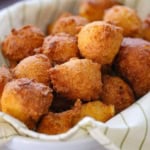 A close-up view of a pile of Traditional Southern Hush Puppies in a basket lined with a striped linen.