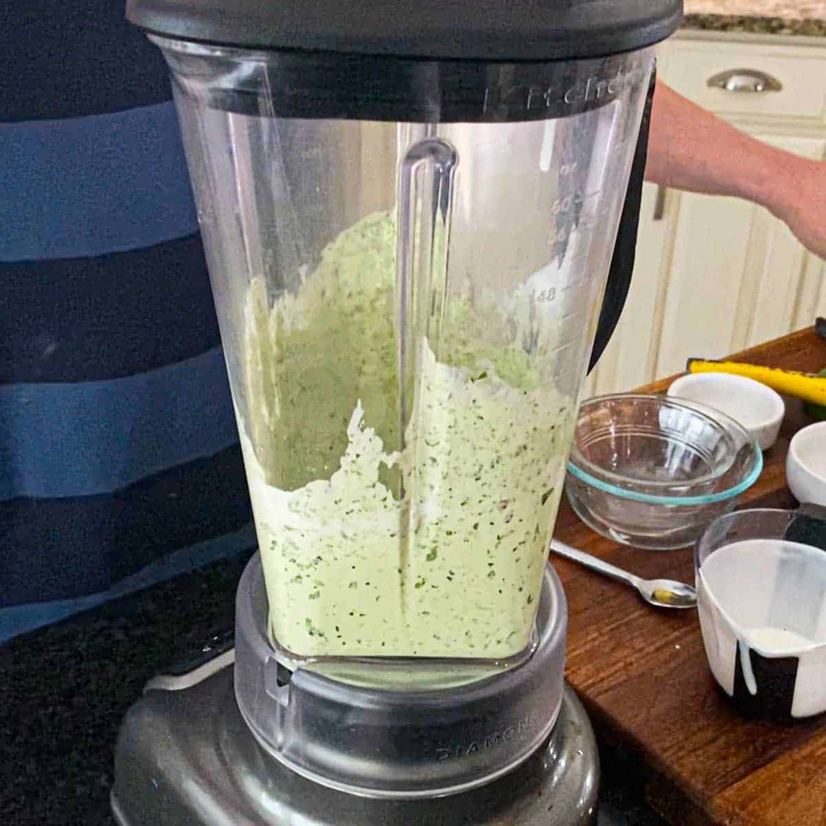 A person puréing Jalapeño-Lime Sauce in a kitchen blender.