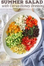 An overhead view of a large platter filled with small piles of roasted bell peppers, jicama, avocado, tomatoes, corn, and black beans.