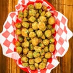 An overhead view of a basket lined with red and white-checkered paper and filled with Classic Southern Fried Okra.