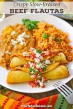 A straight-on view of a white dinner plate filled with a serving of two side-by-side crispy beef flautas next to a mound of Mexican rice and refried beans.