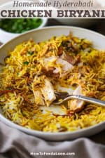 A partially eaten chicken thigh in a shallow bowl filled with a serving of Hyderabadi Chicken Biryani with a fork in the middle of the dish.