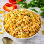 A close-up view of a shallow white bowl filled with freshly prepared Cajun pasta salad and garnished with chopped parsley.