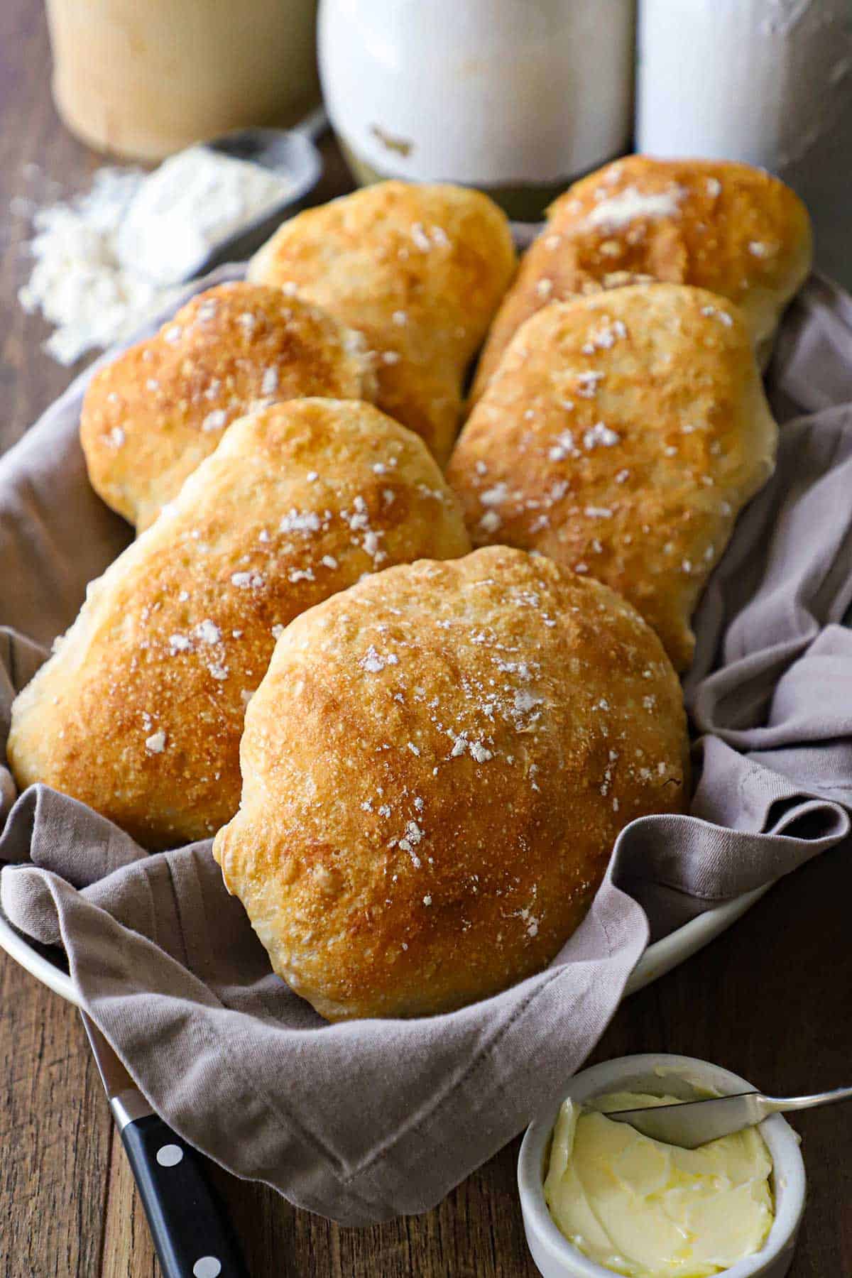 A front-view of a basket lined with a grey cloth napkin and filled with Bakery-Style Homemade Ciabatta Buns.