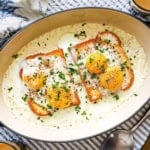 An overhead view of French Baked Eggs with Cream in an oval baking dish topped with snipped chives.