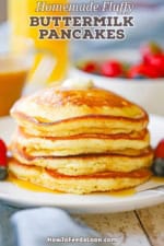 A stack of four homemade fluffy buttermilk pancakes topped with maple syrup on a white plate.
