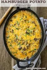 An overhead view of a hamburger potato casserole in an oval baking dish with a wooden spoon nearby.