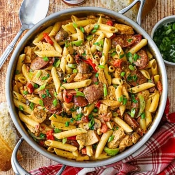 An overhead view of a large silver skillet filled with freshly prepared Creamy Cajun Chicken and Sausage Pasta.