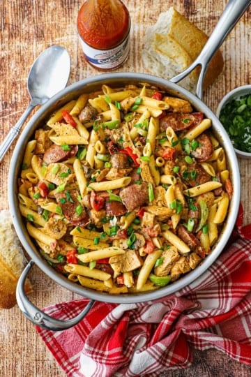 An overhead view of a large silver skillet filled with freshly prepared Creamy Cajun Chicken and Sausage Pasta.