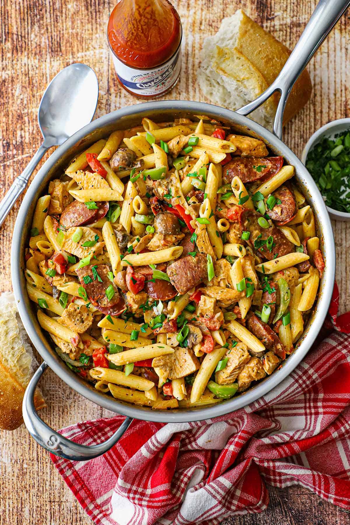 An overhead view of a large silver skillet filled with freshly prepared Creamy Cajun Chicken and Sausage Pasta.