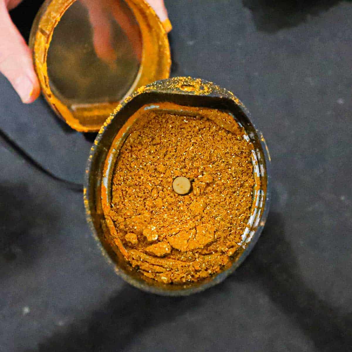 An overhead view of a spice grinder filled with pulverized homemade curry powder.