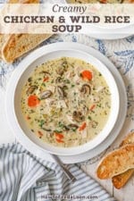 An overhead view of a shallow white bowl filled with a serving of Creamy Chicken and Wild Rice Soup with several slices of toasted bread next to the bowl.
