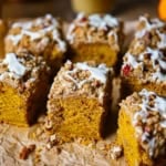 A straight-on view of a Pumpkin Spice Coffee Cake that has been cut into squares with a pecan streusel and maple glaze on top.