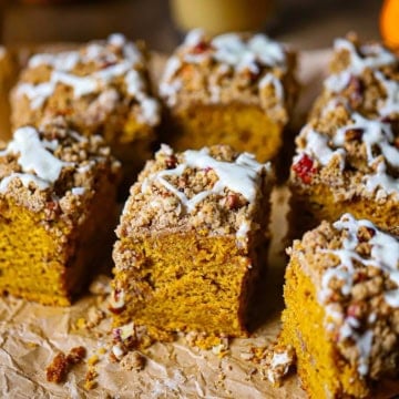 A straight-on view of a Pumpkin Spice Coffee Cake that has been cut into squares with a pecan streusel and maple glaze on top.