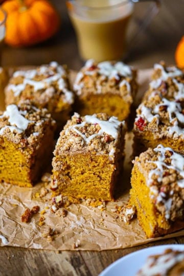A straight-on view of a Pumpkin Spice Coffee Cake that has been cut into squares with a pecan streusel and maple glaze on top.