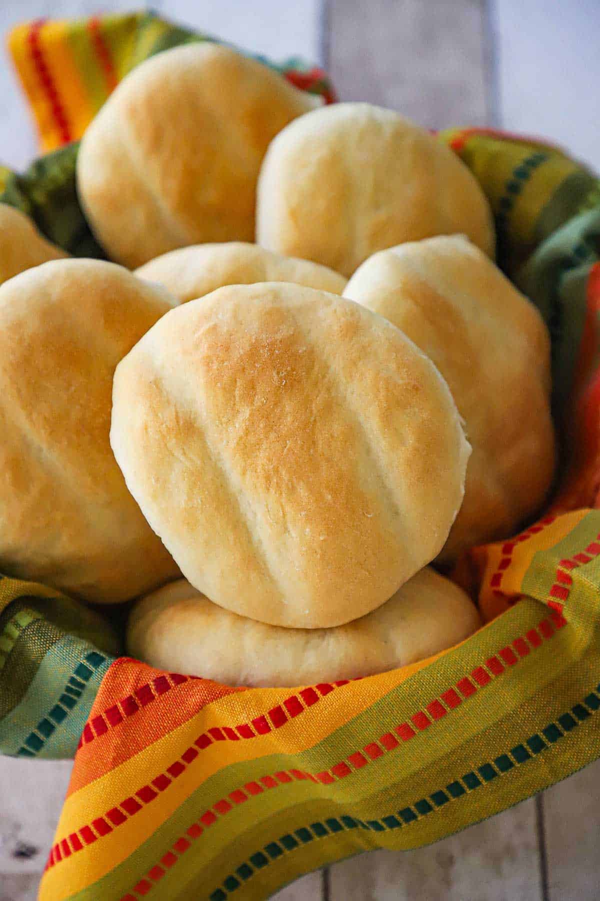 A straight-on view of a bread basket lined with a festive linen and filled with homemade telera rolls.