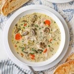 An overhead view of a wide, shallow soup bowl filled with a serving of Creamy Chicken and Wild Rice Soup with slices of toast on both sides of the bowl.