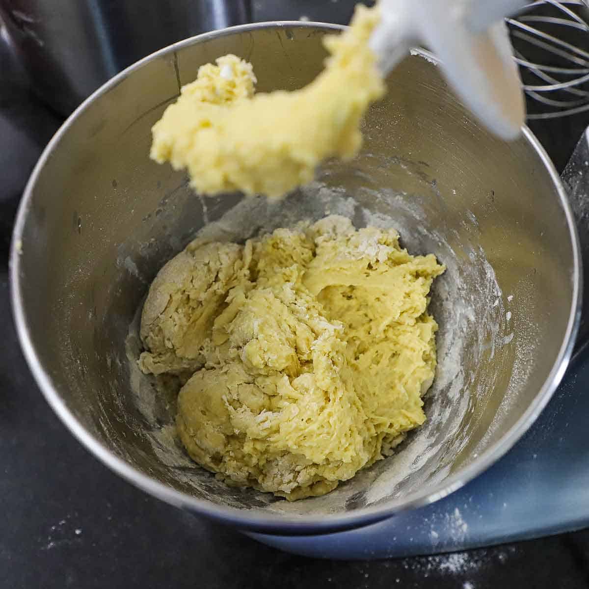 A downward view of a shaggy dough that has been mixed and formed in the bowl of a stand mixer.