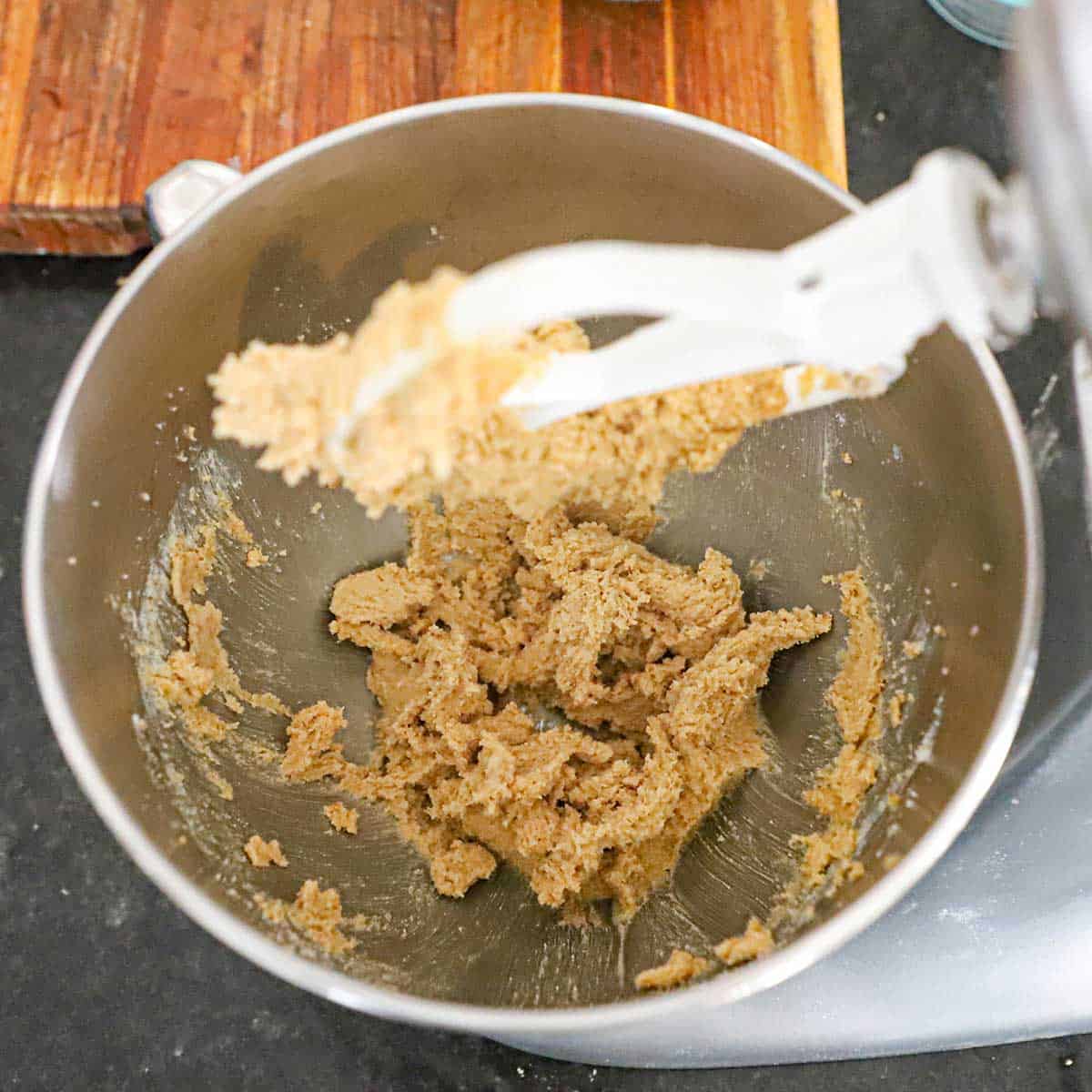 An overhead view of a stand mixer that has softened butter that has been whipped together with granulated sugar and brown sugar to create a fluffy mixture.